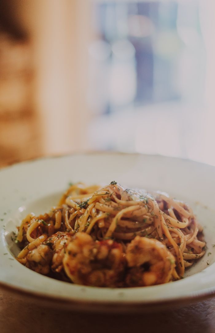 get-in-touch A mouthwatering shrimp pasta served on a white plate with artistic presentation.