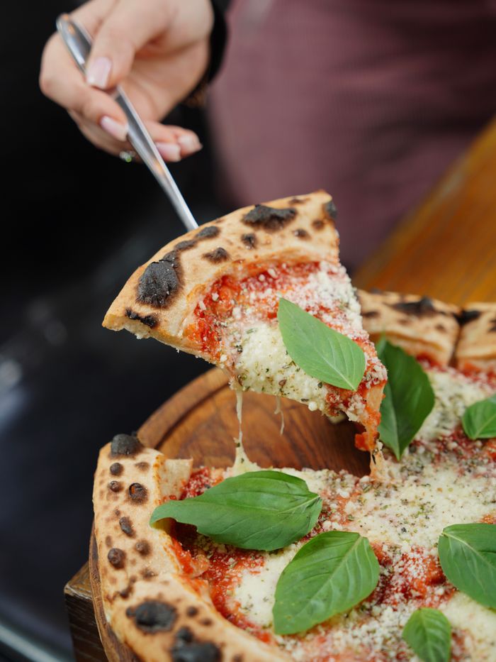services-02 Delicious pizza slice being served, topped with fresh basil and molten cheese.