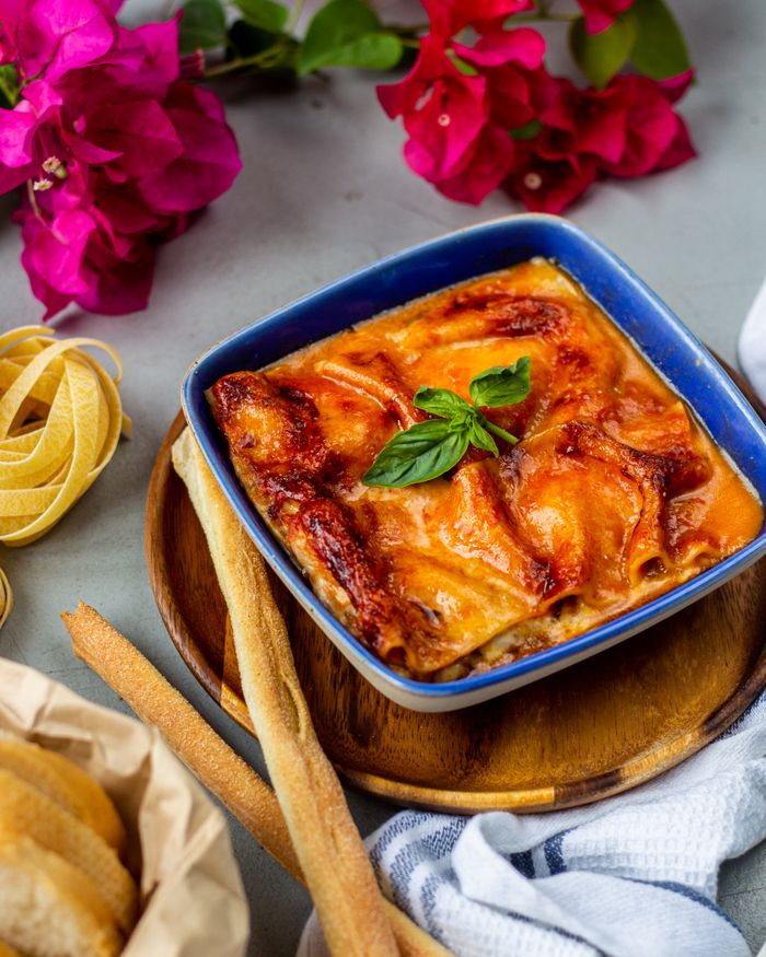 services-04 Enjoy the rich flavors of homemade Italian lasagne served in a blue dish with a basil garnish.